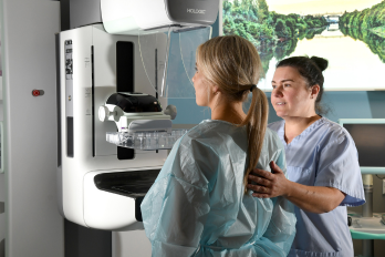 Woman having a mammogram with a member of staff present. 