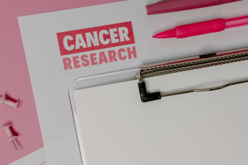 White paper on pink background with pink and white text reading 'Cancer research' 
